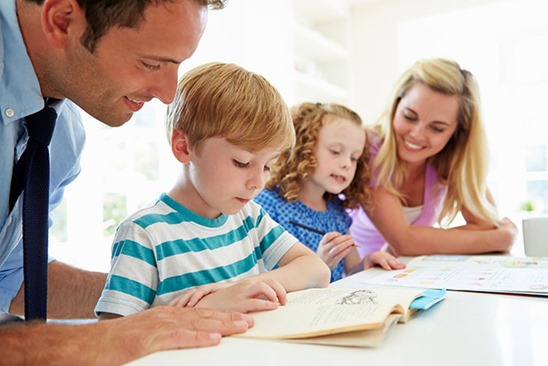 Parents Helping Children With Homework In Kitchen